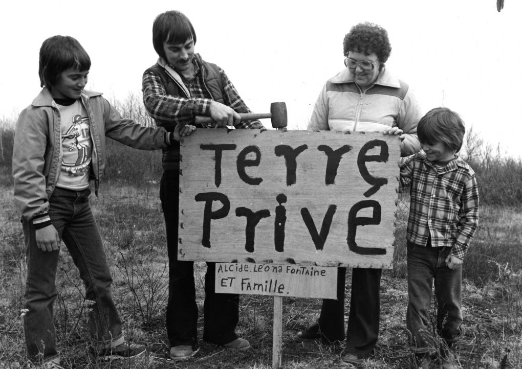 Manifestation par une famille réclamant symboliquement sa terre. Photo du journal L'Évangéline, collection CEAAC, 17 avril 1980.